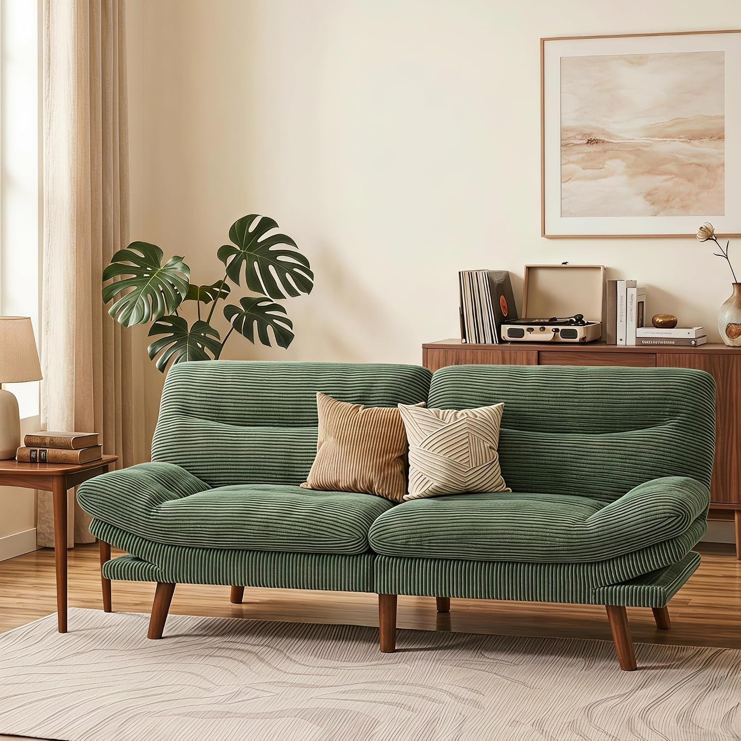 Green corduroy futon sofa shown as a two-seat sofa in a living room with wood legs and throw pillows