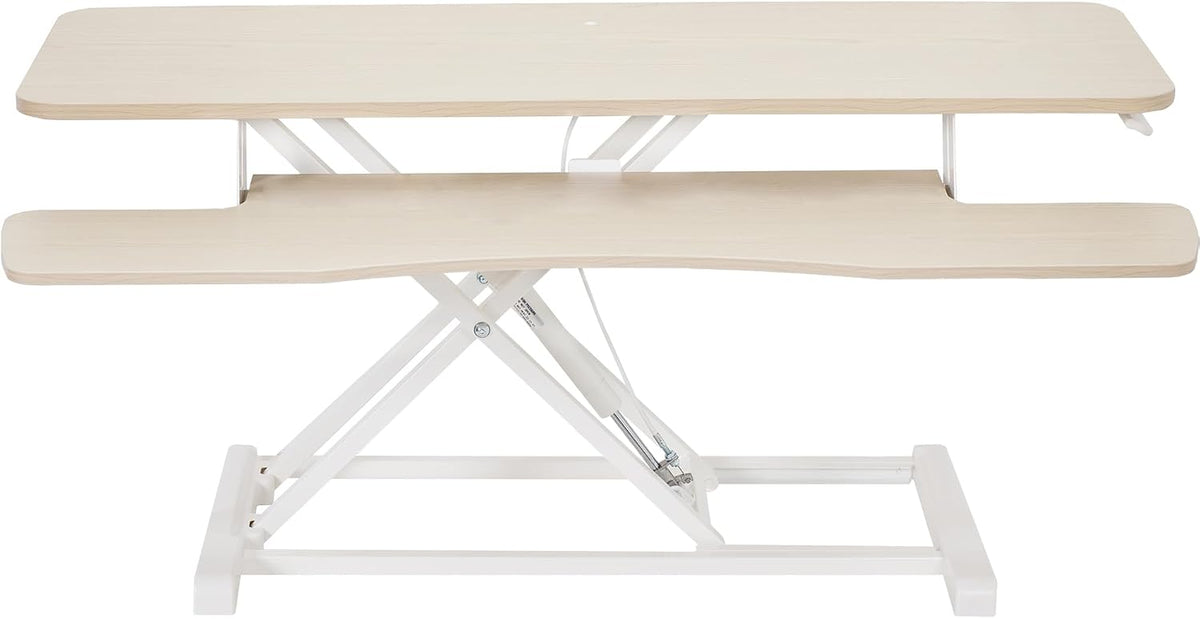 Front view of a light wood finish standing desk converter showing the scissor lift and keyboard tray.