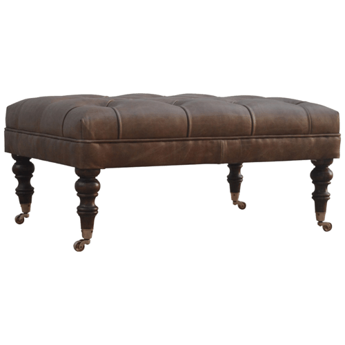 Brown leather ottoman viewed from the front at an angle, showing its buttoned top and legs.