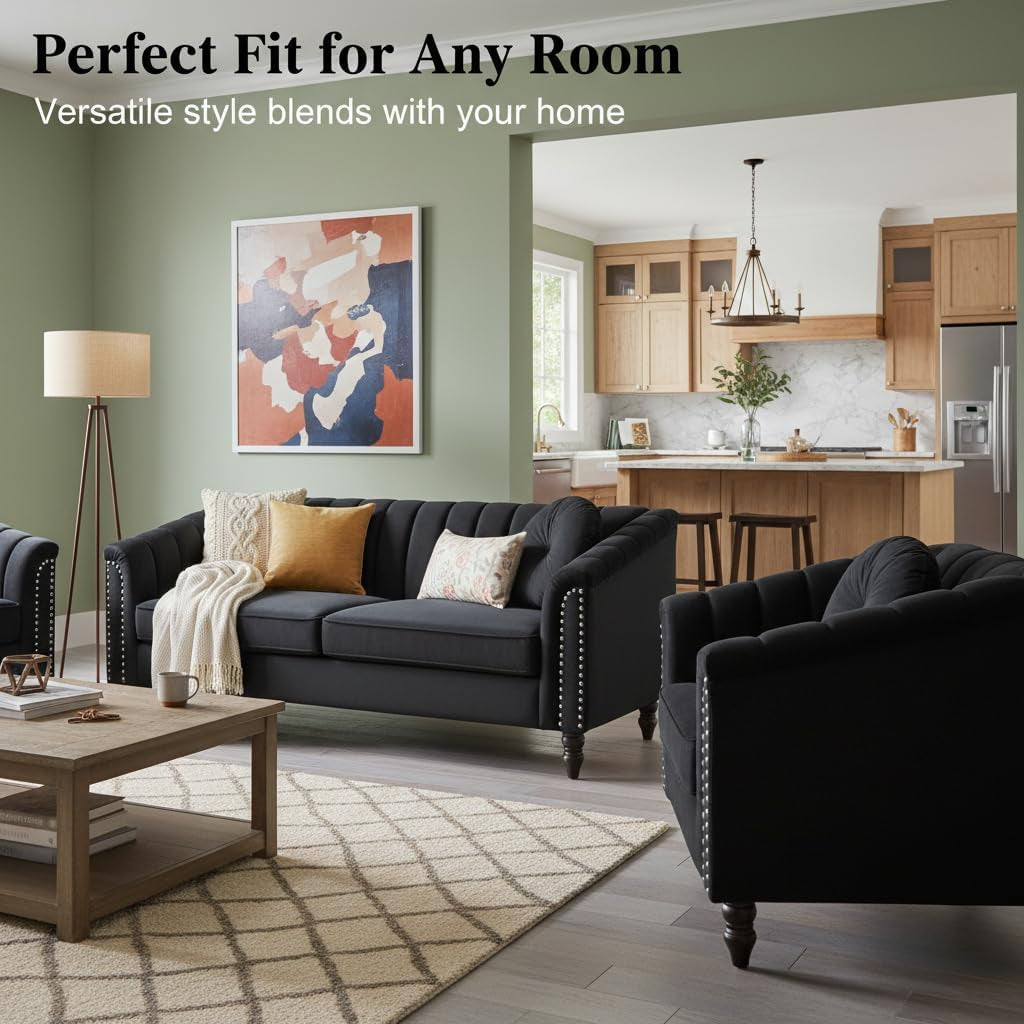 Black velvet three-seat sofa and armchair in an open-plan living area with green accent wall and kitchen in background