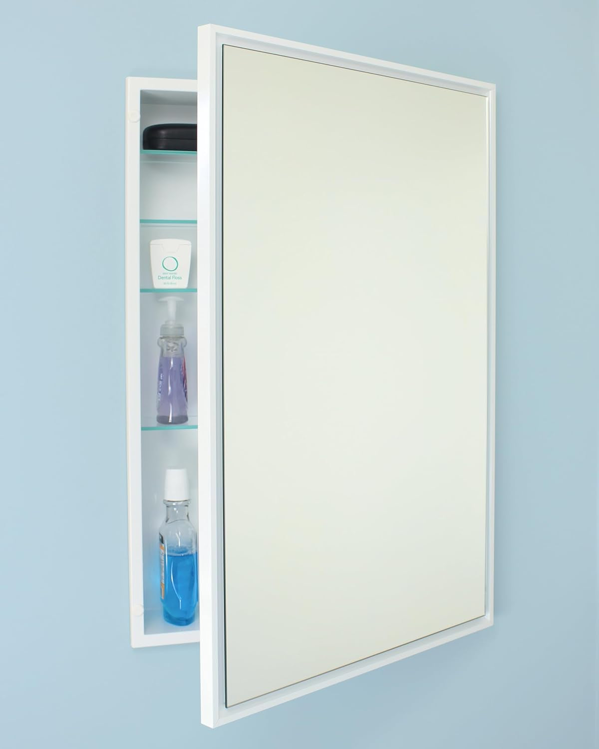 White-framed recessed mirror door partially open, showing three interior glass shelves with toiletries
