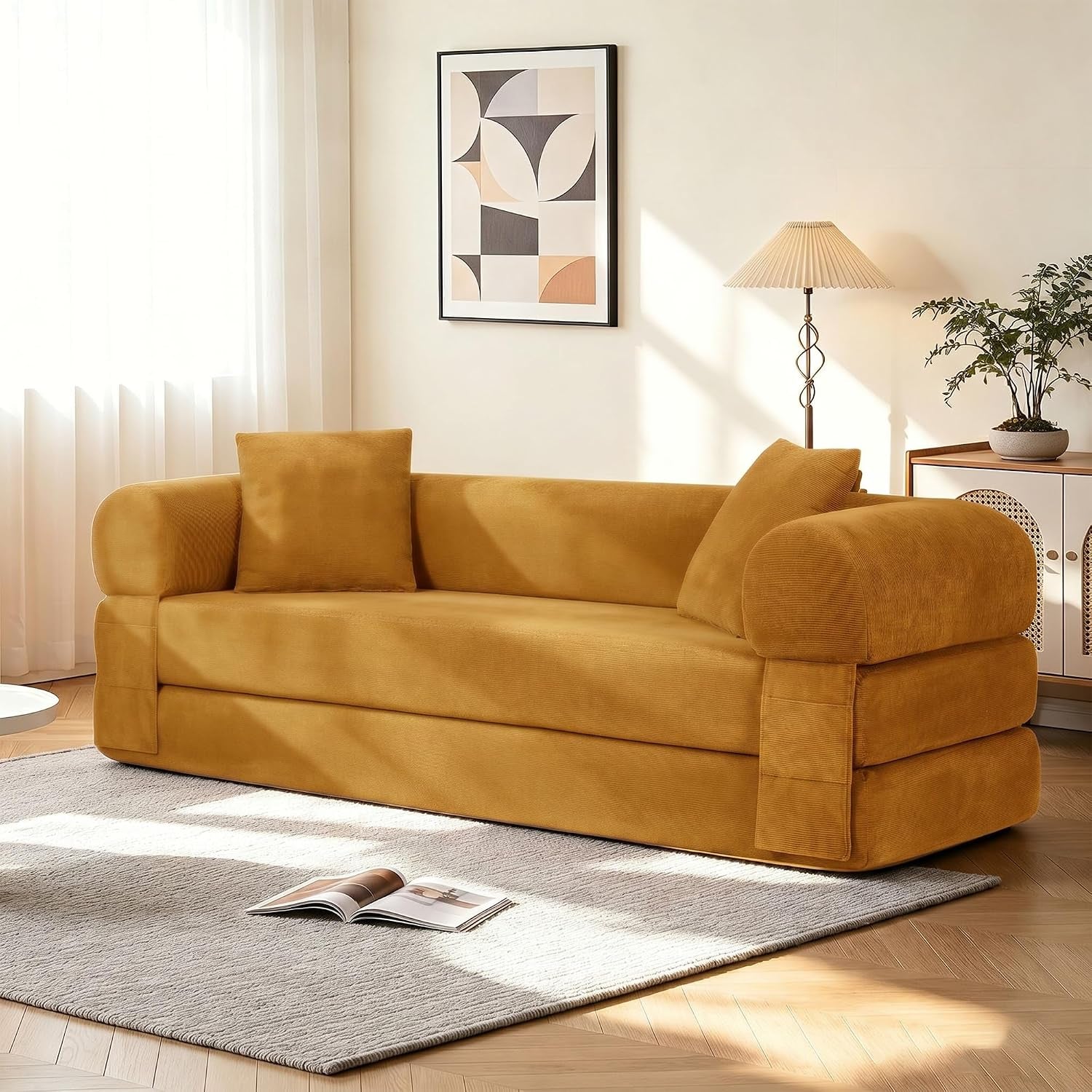 Golden mustard corduroy convertible sofa with two matching square pillows in a sunlit living room.