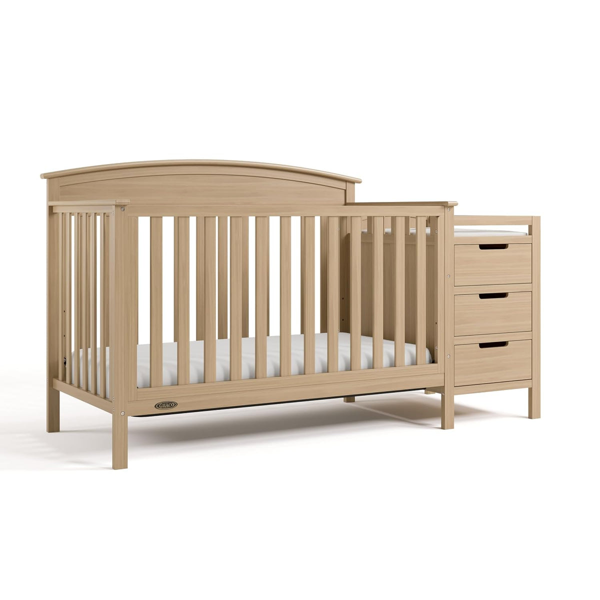 Natural wood-finish crib shown in a three-quarter view with attached three-drawer changer on the right.