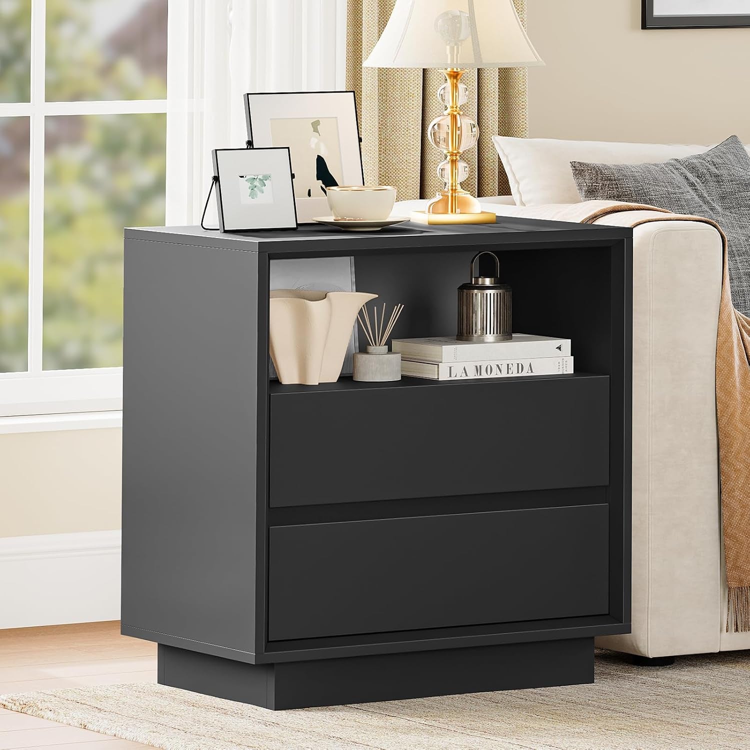 Single black nightstand with open shelf beside a sofa, angled front view in a bright room