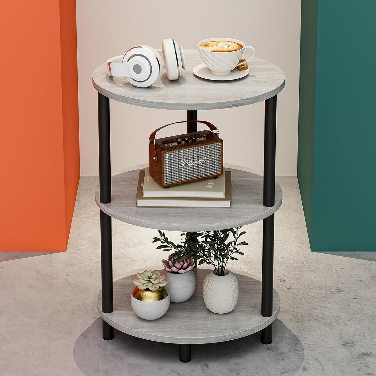 Light gray three-tier round end table with headphones, cup, radio, and small potted plants