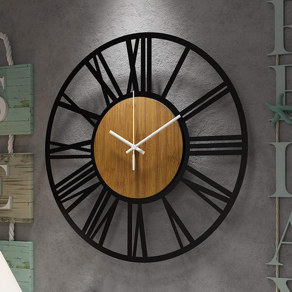 Black openwork wall clock with wood center mounted on textured gray wall beside coastal wooden decor