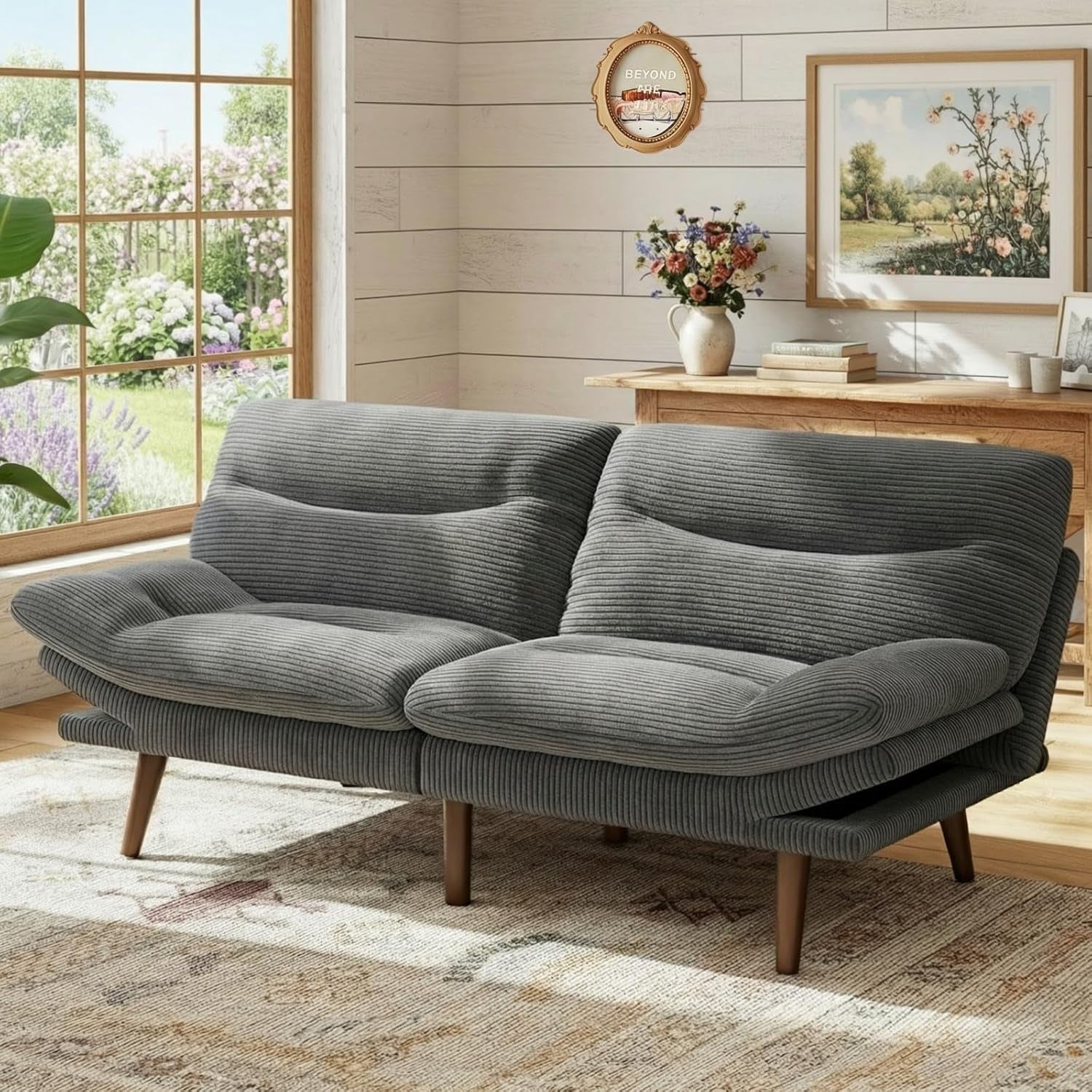 Gray corduroy futon loveseat shown in a bright room with wood-paneled walls