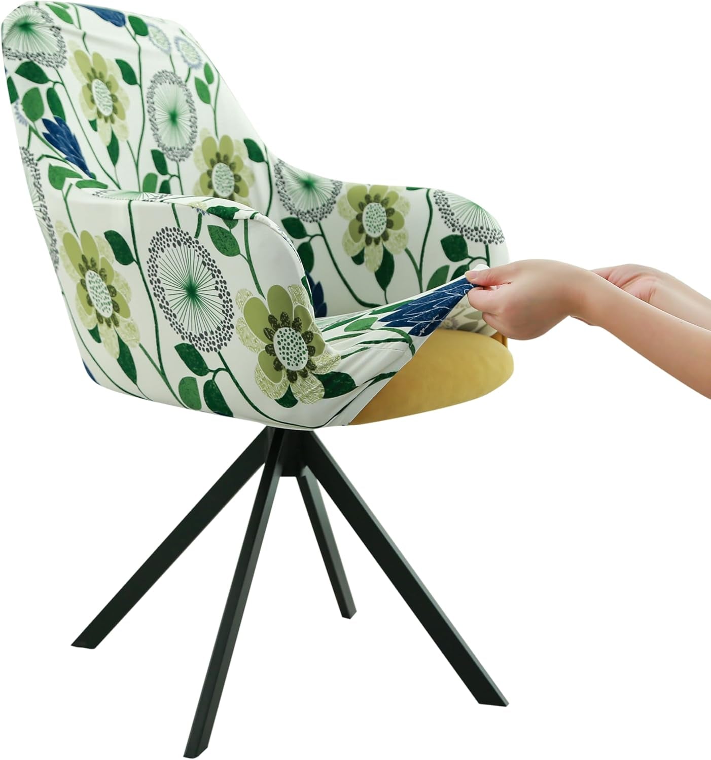 Side view of a swivel armchair with a green floral stretch cover being pulled over the seat by two hands.