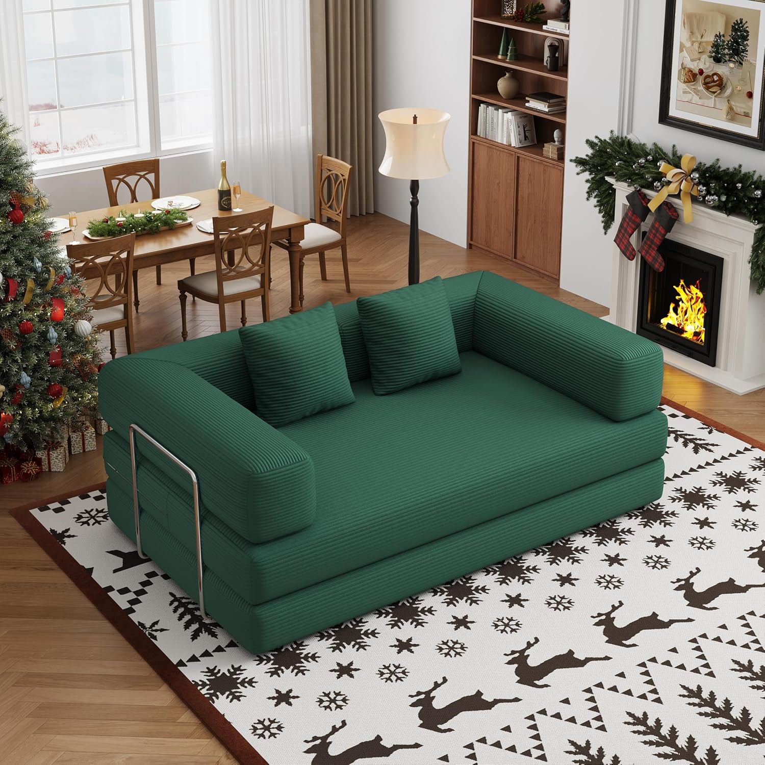 Angled view of a green corduroy convertible sofa bed on a patterned rug in a holiday-styled room