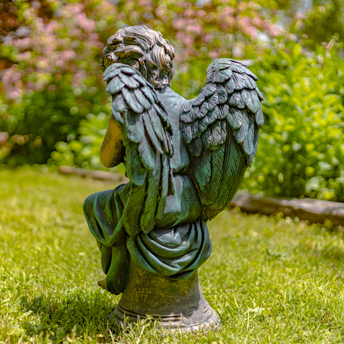 Rear view of the seated angel statue, with its layered wings filling much of the frame.
