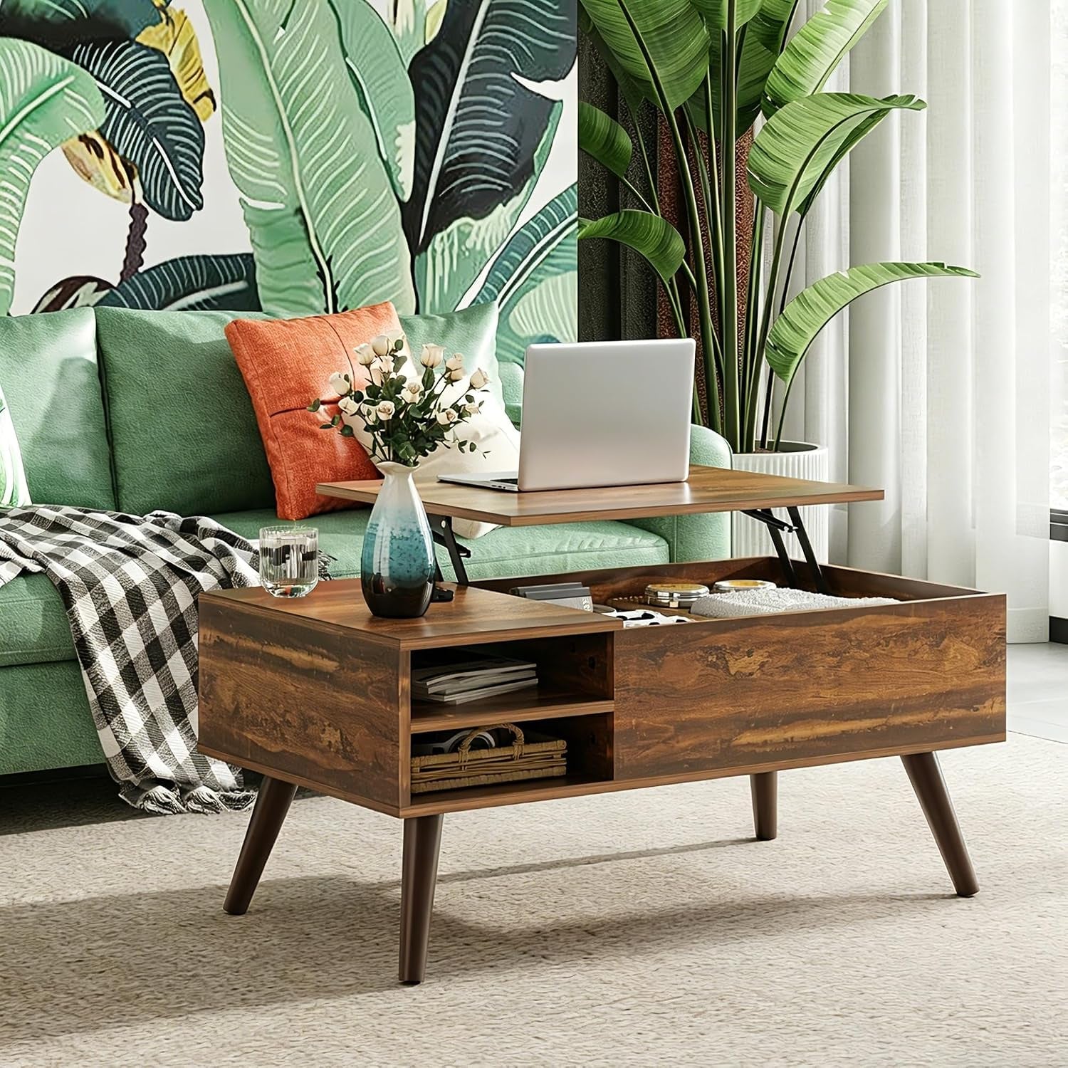 Styled living room scene with the lift-top coffee table raised, a laptop and vase on top, and a green sofa behind it.
