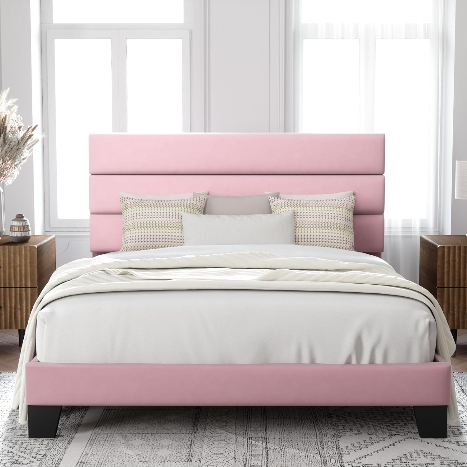 Front view of a pink upholstered bed with three horizontal headboard panels and black legs.
