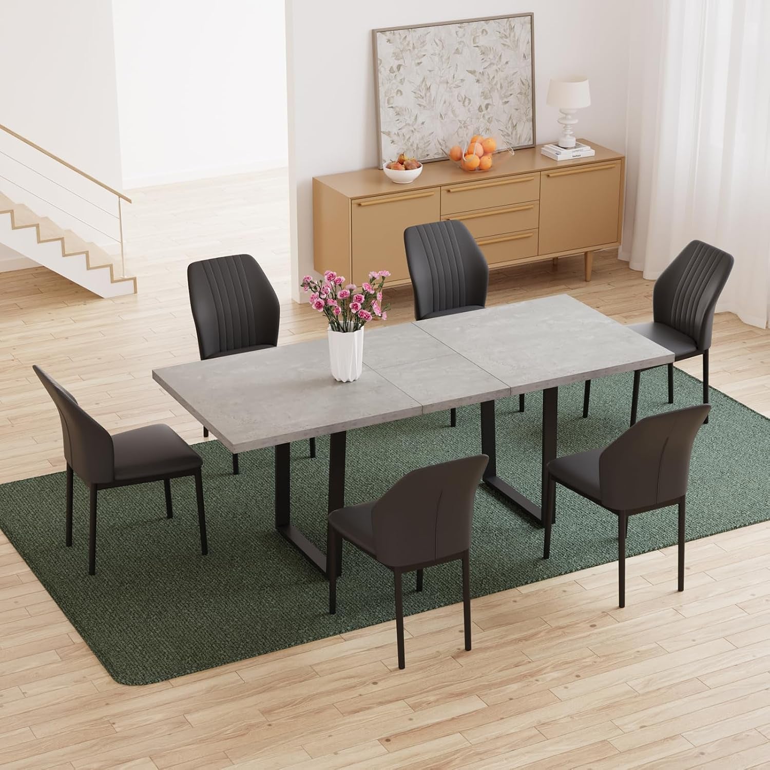 Overhead view of a long table with six chairs placed on a green rug, with a sideboard and framed art in the background.