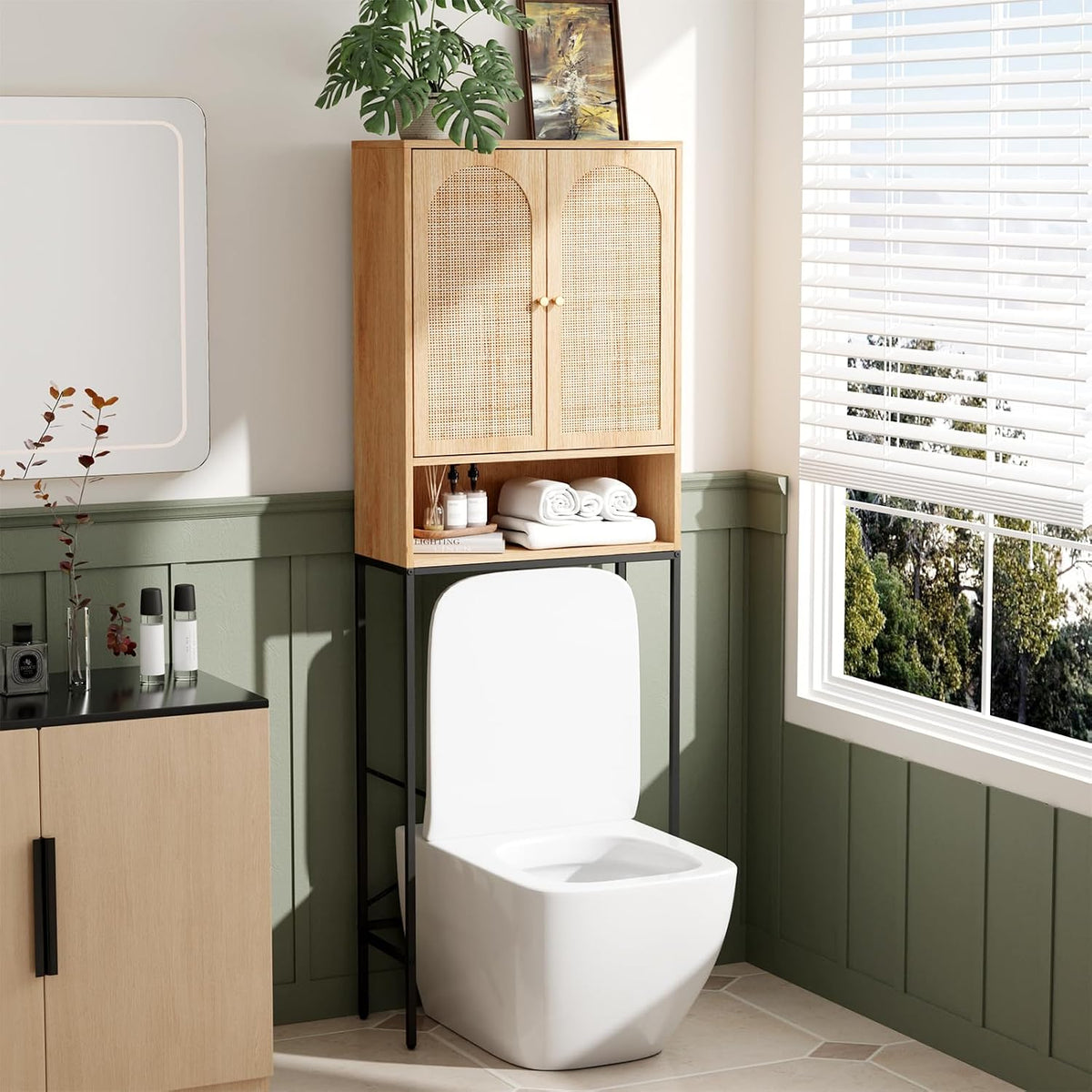 Natural wood cabinet with woven cane doors on a black metal frame placed over a toilet in a bright bathroom