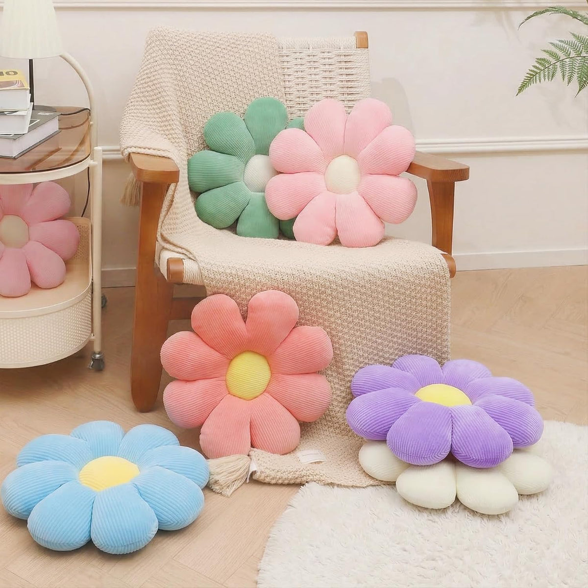 Mint green and pink daisy throw pillows on a woven armchair and floor, warm neutral room setting