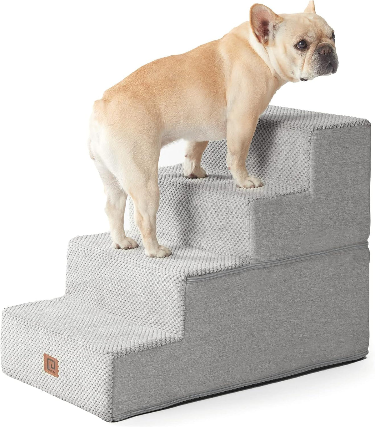 Cropped side view of a tan French bulldog standing on the upper steps of light gray foam stairs.