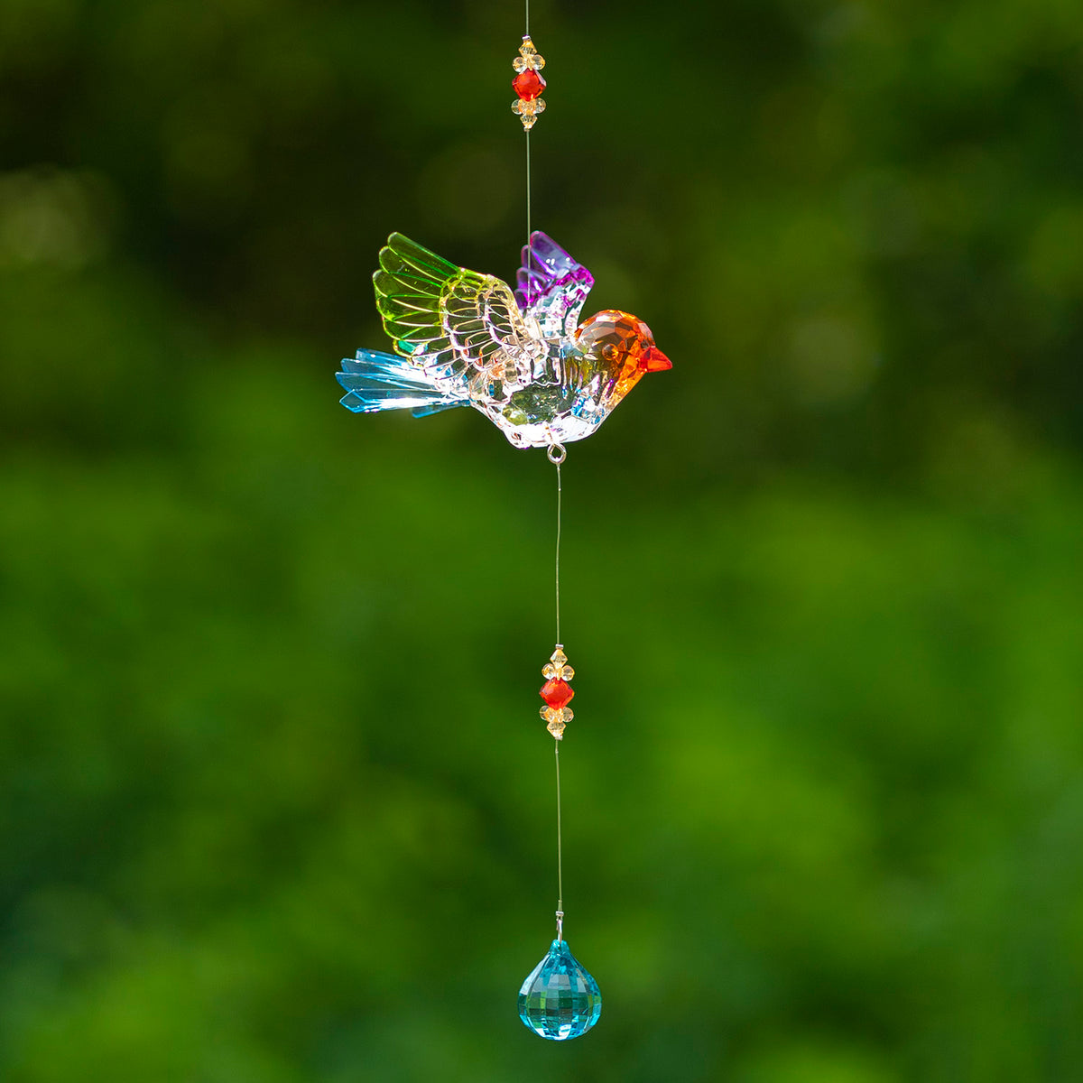 Colorful acrylic bird ornament hanging above red and gold beads and a turquoise teardrop dangle.