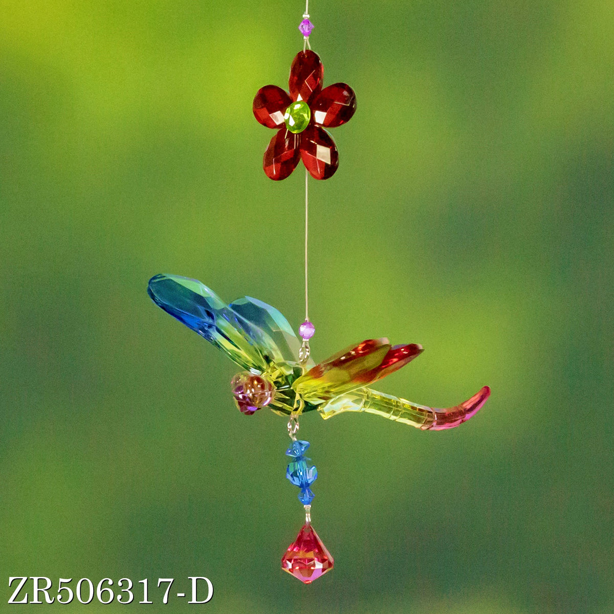 A faceted dragonfly with blue, yellow, and pink wings hangs beneath a dark red flower and blue beads.