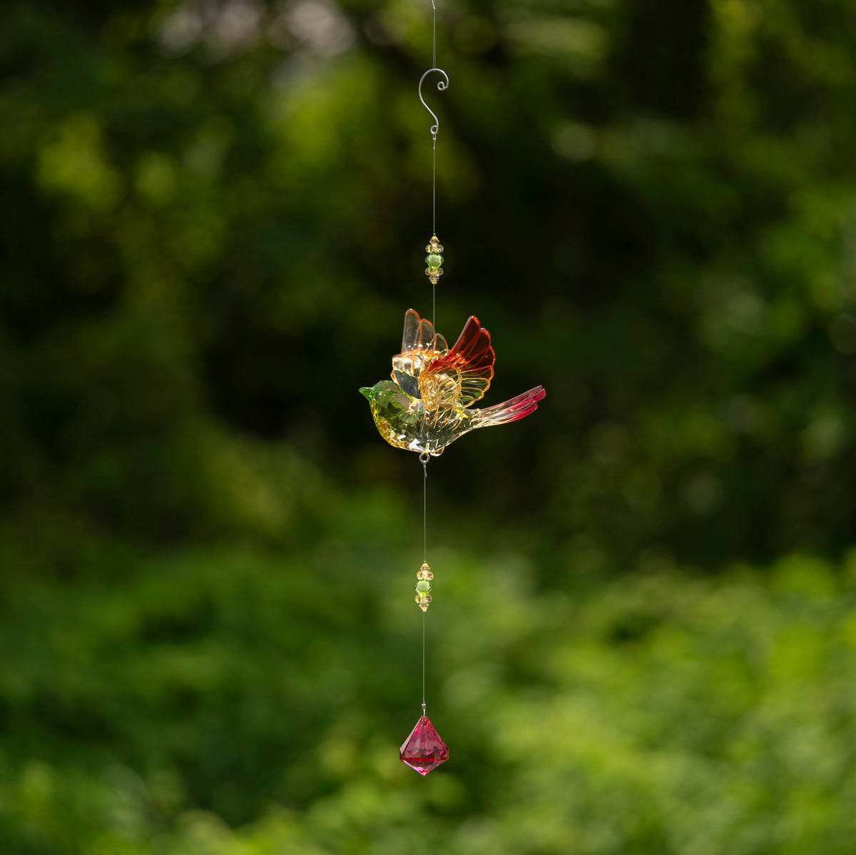 A small multicolored acrylic bird hangs from a long strand with beads and a red faceted drop.