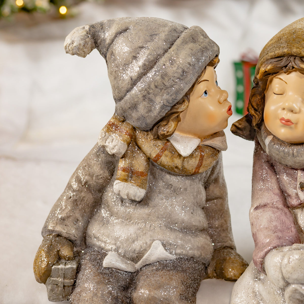 A gray-clad winter figure leans toward a partially visible rosy-clad figure, their faces nearly touching.