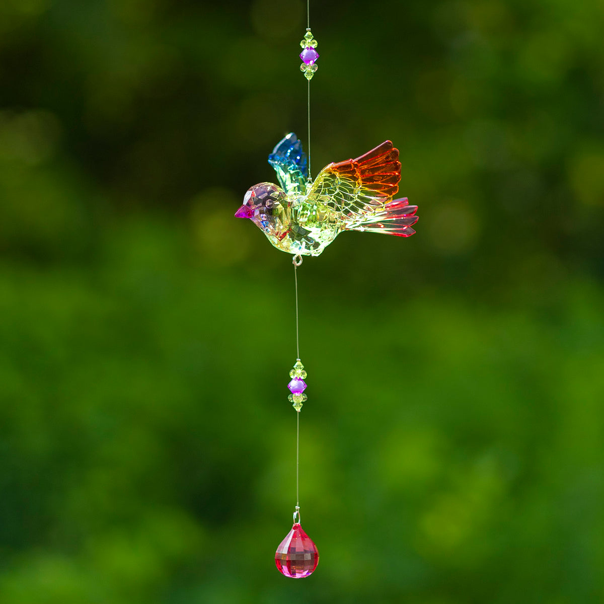 Multicolored acrylic bird ornament hanging on a fine string with bead accents and a pink teardrop dangle.