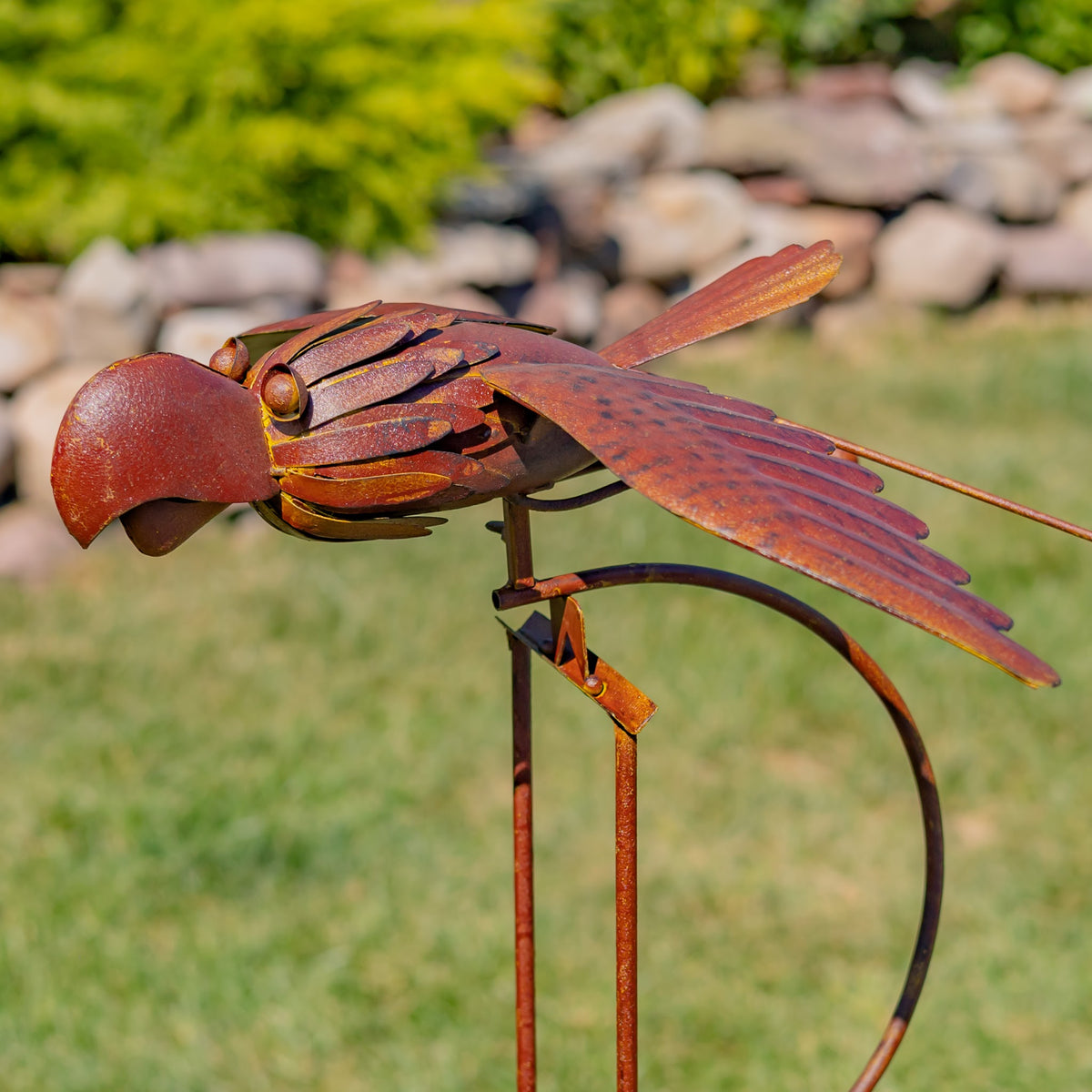 Rust-colored bird ornament seen from the other side, showing its layered wings, curved rocker, and stake.