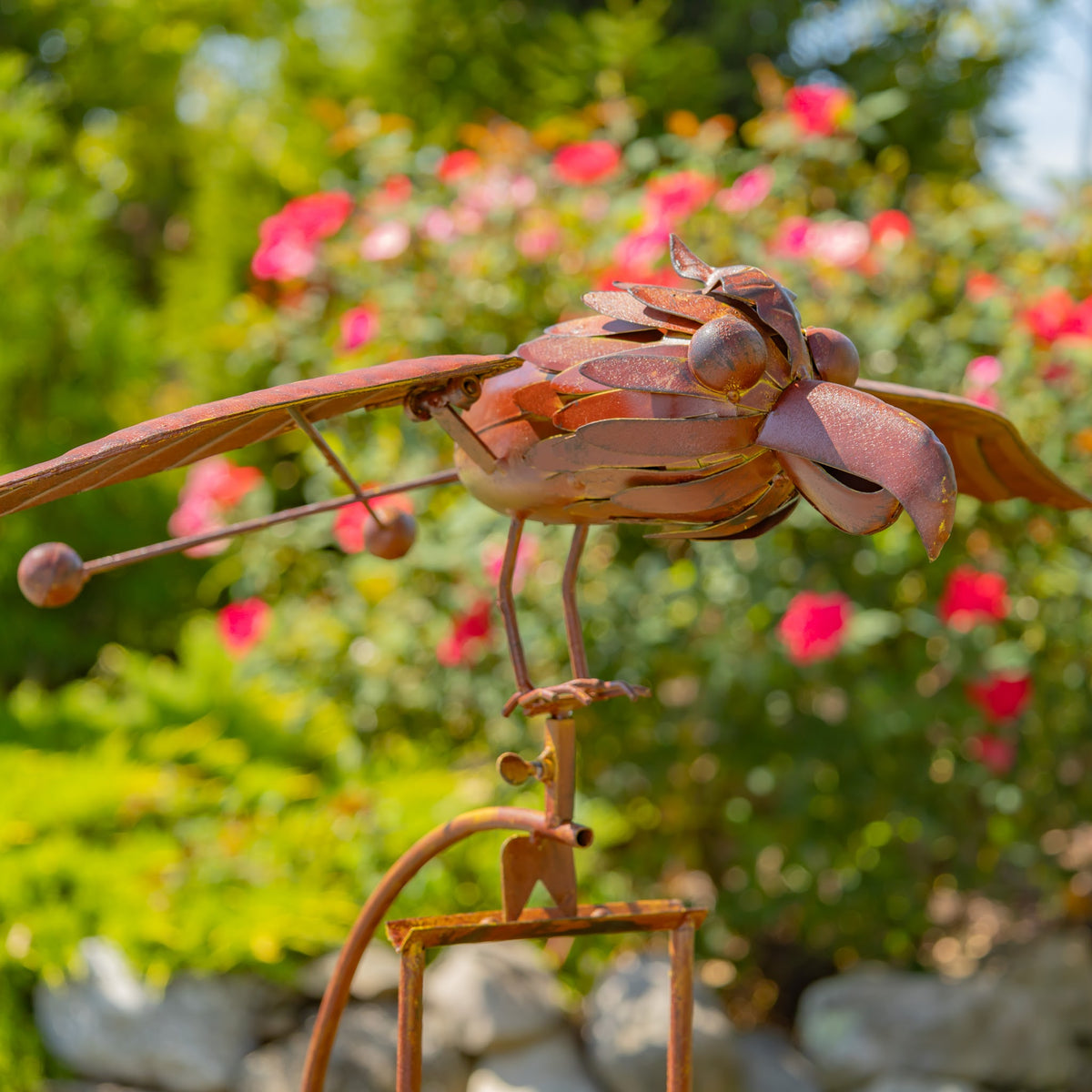 Close view of the rust-finish metal hawk sculpture, showing layered body plates, curved beak, and spread wings.