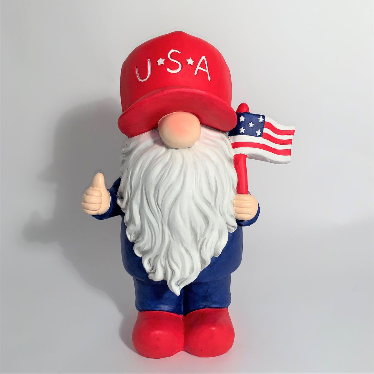 Red, white and blue garden gnome holding a flag, front view against a plain background