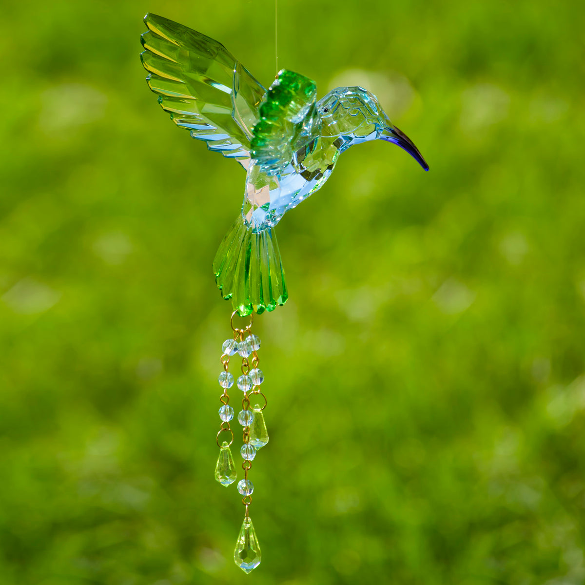 Green faceted hummingbird with raised wings and a dangling strand of clear and green beads.