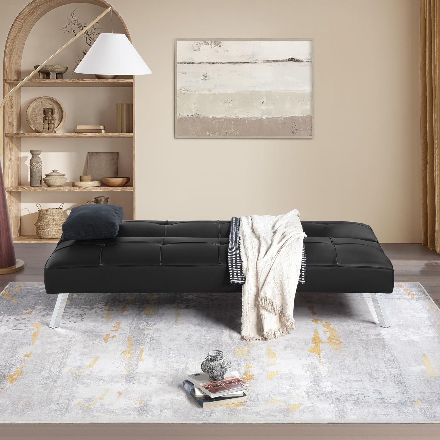 Styled living room scene with the futon set up flat as a bed on a patterned rug.