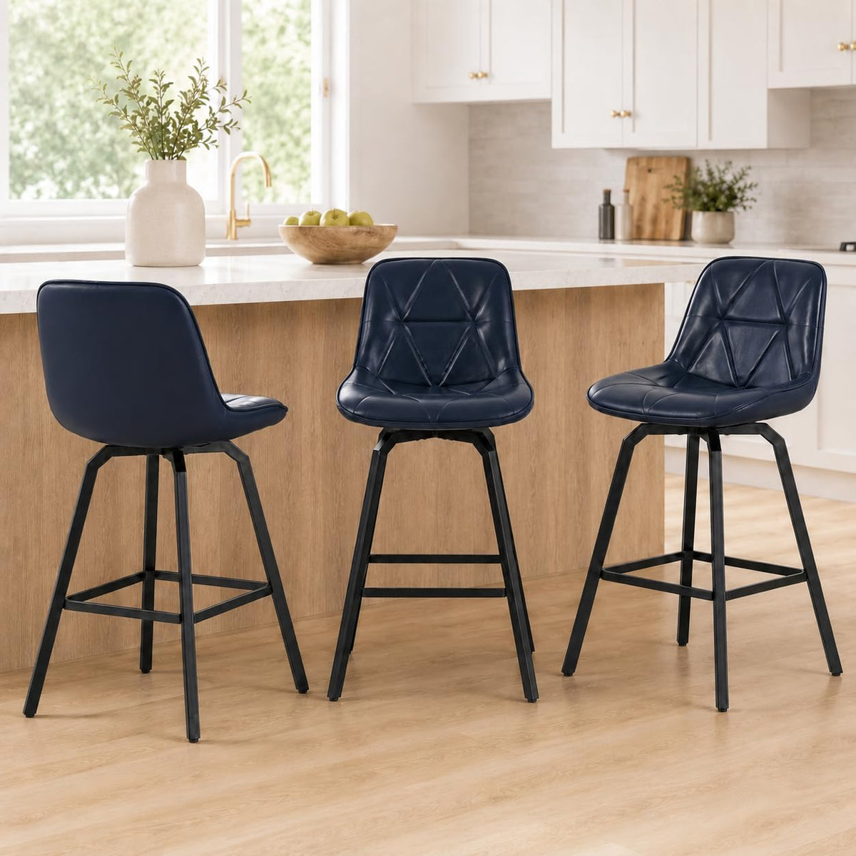 Three dark navy faux-leather counter stools with quilted seats and black metal bases arranged at a wood-front island.