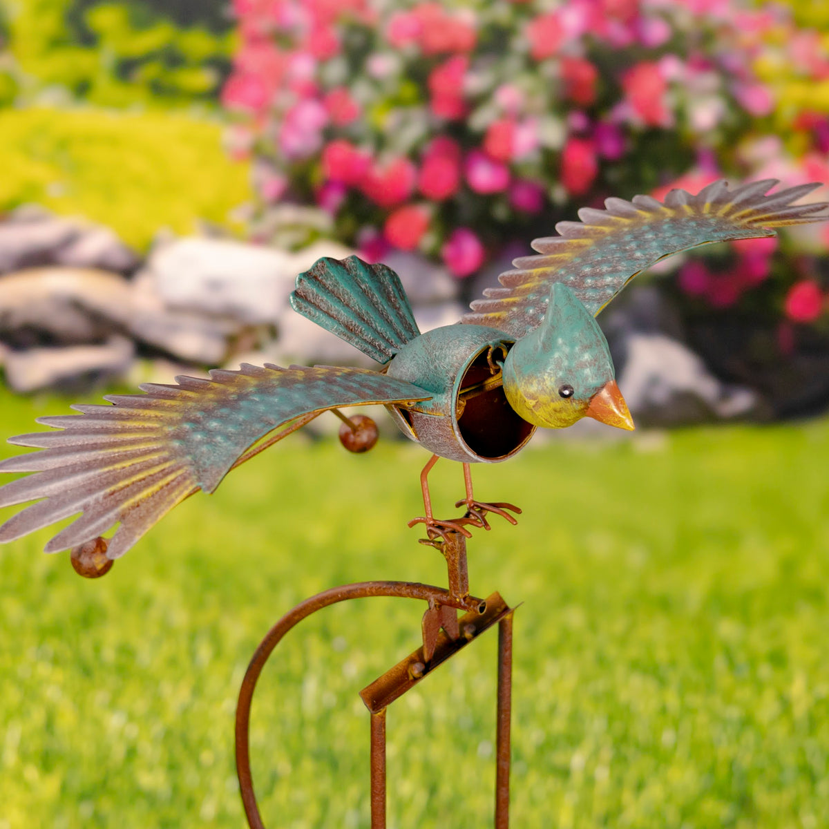 Close-up of colorful bird with wings spread on its garden stake among flowers