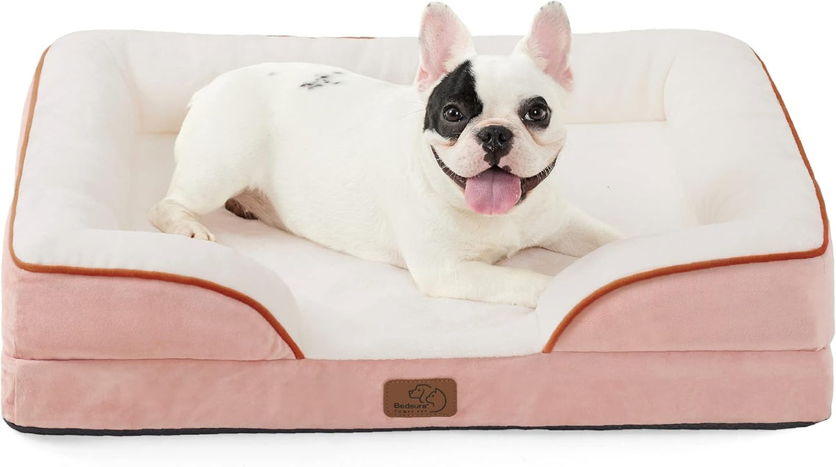 Pink outer bolsters and cream sleeping surface with a smiling white dog lying in the center