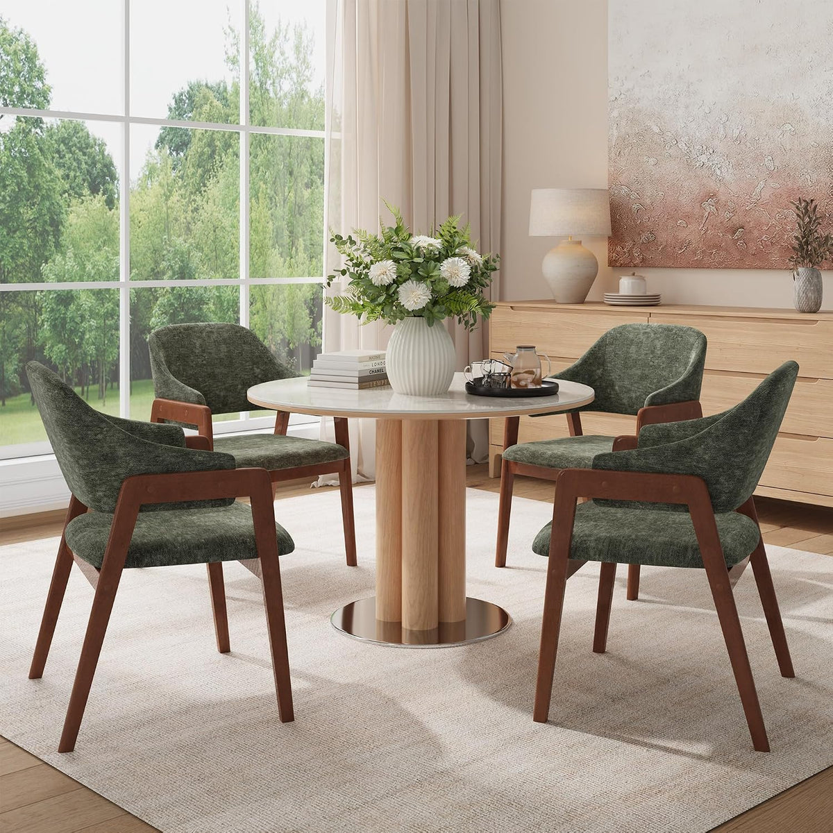 Close dining view of four sage-green upholstered armchairs around a round table with window light.