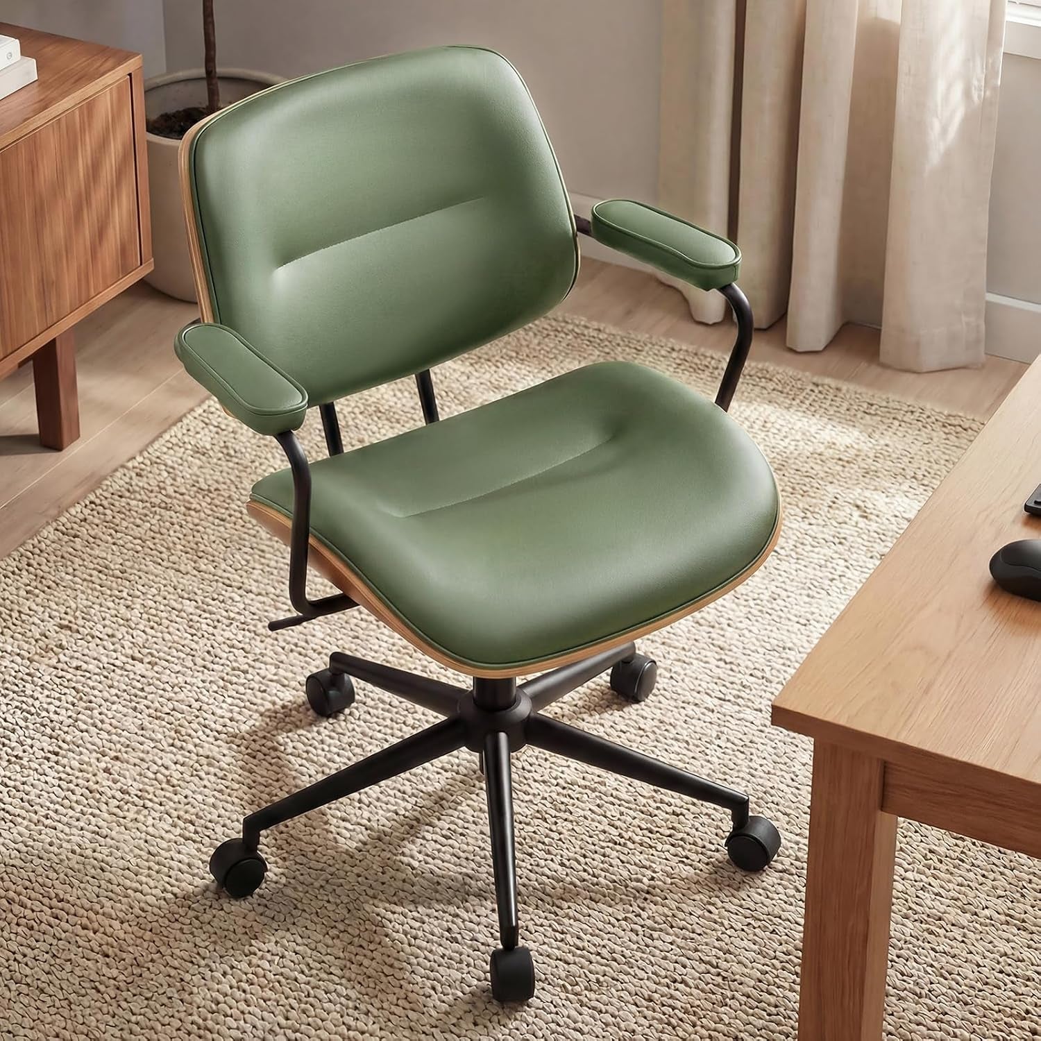 Green mid-century office chair angled front view with wooden curved back, padded armrests and black five-star base in a homey