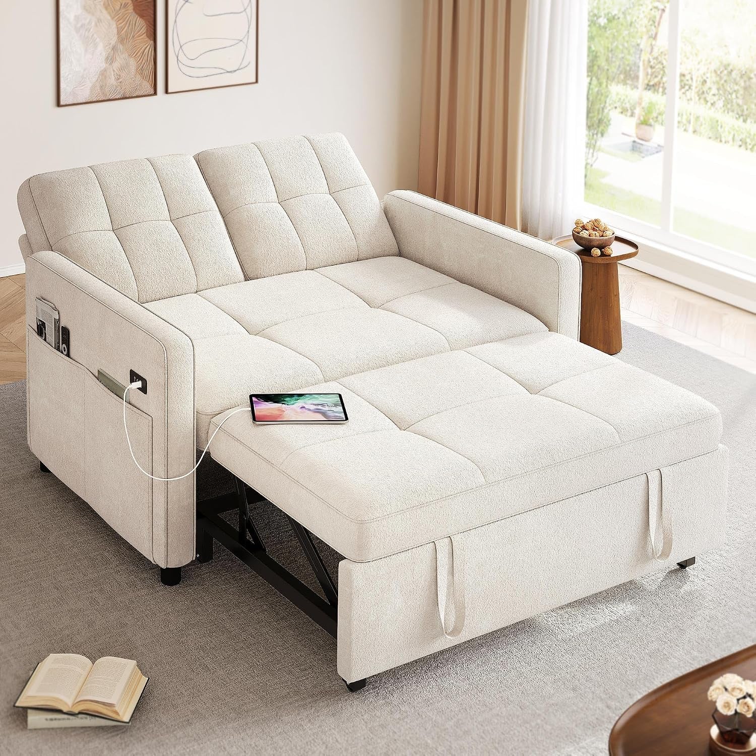 Light cream convertible futon pulled out as a bed showing side pocket and a tablet charging on the surface