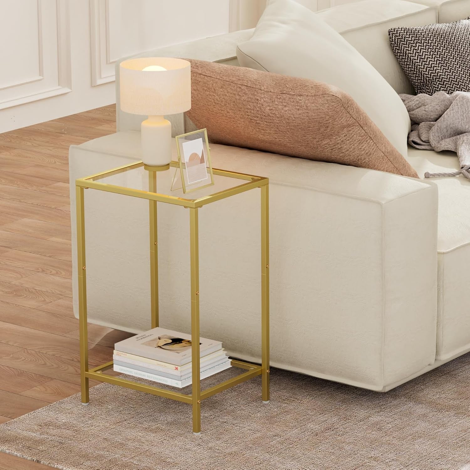 Gold tempered glass side table positioned beside a sofa with books on the lower shelf