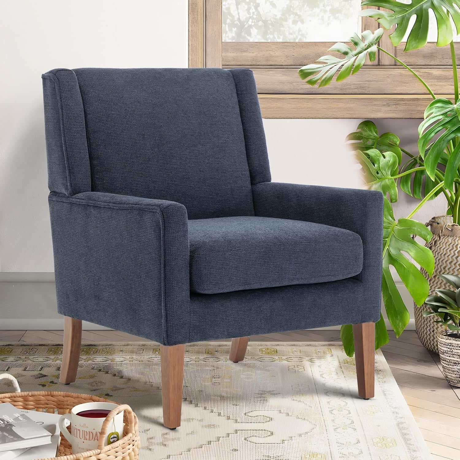 Dark charcoal wingback accent chair with tapered wooden legs next to houseplants