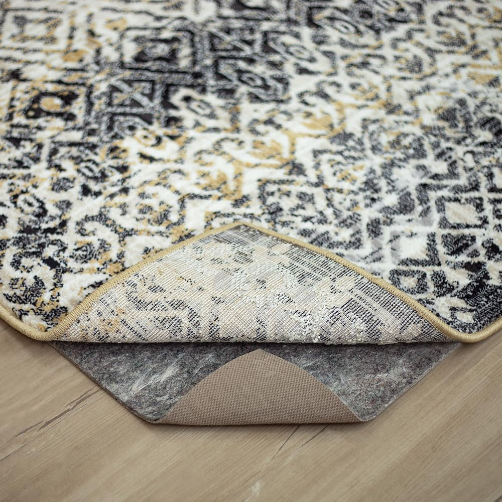 Folded rug corner revealing the pad beneath, showing the rug's stitched binding and the pad's cut corner shape.