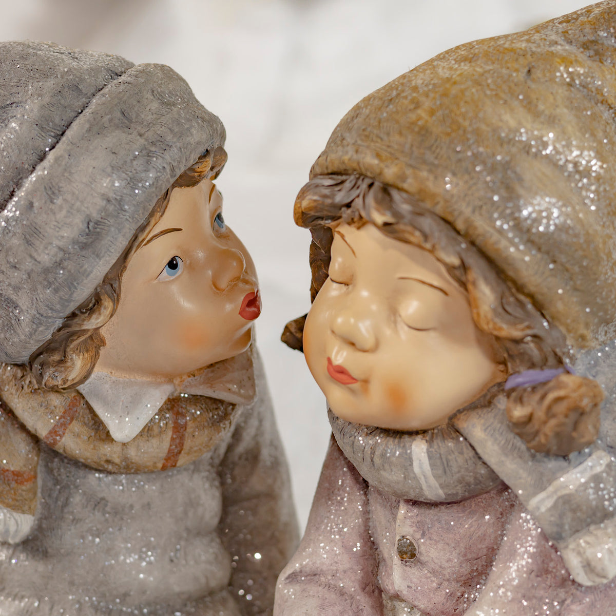 Close-up of the two figurines facing each other, with rosy cheeks and glittery hats.