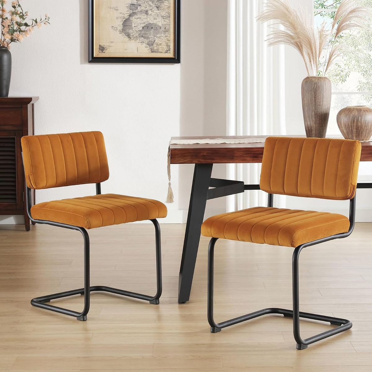 Two mustard velvet cantilever chairs shown beside a wood table with decorative vases