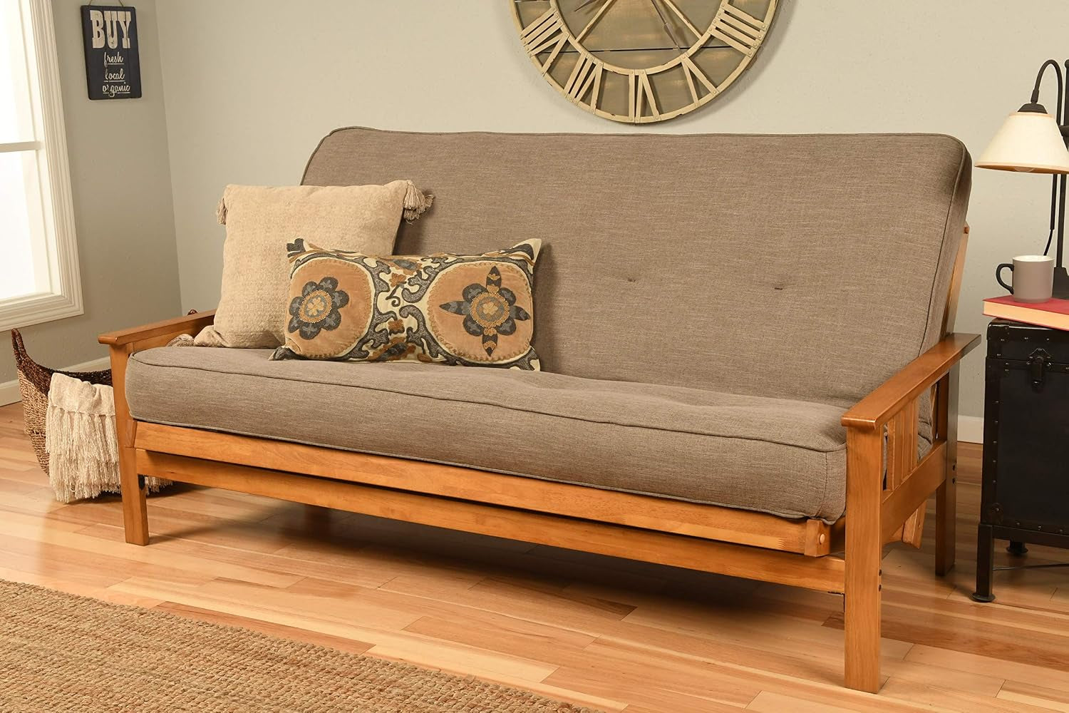 Straight-on view of a full-size futon sofa in sofa position with a taupe fabric mattress and a patterned lumbar pillow on a
