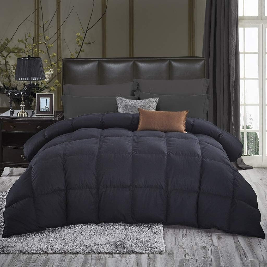 Front view of a made bed with black comforter showing large square baffle pattern and headboard backdrop