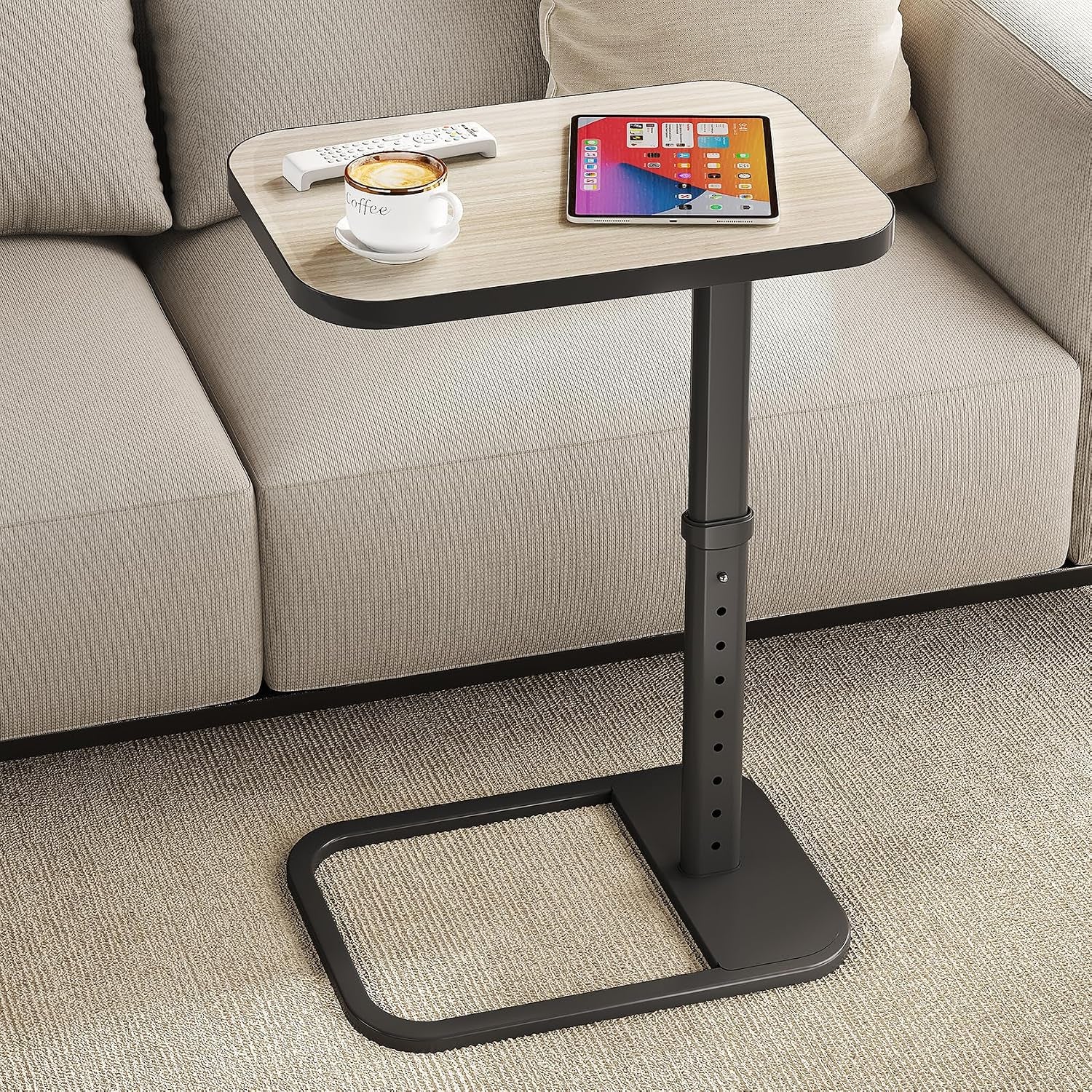 C-shaped side table with light wood top and black base next to a sofa holding a tablet and coffee mug.