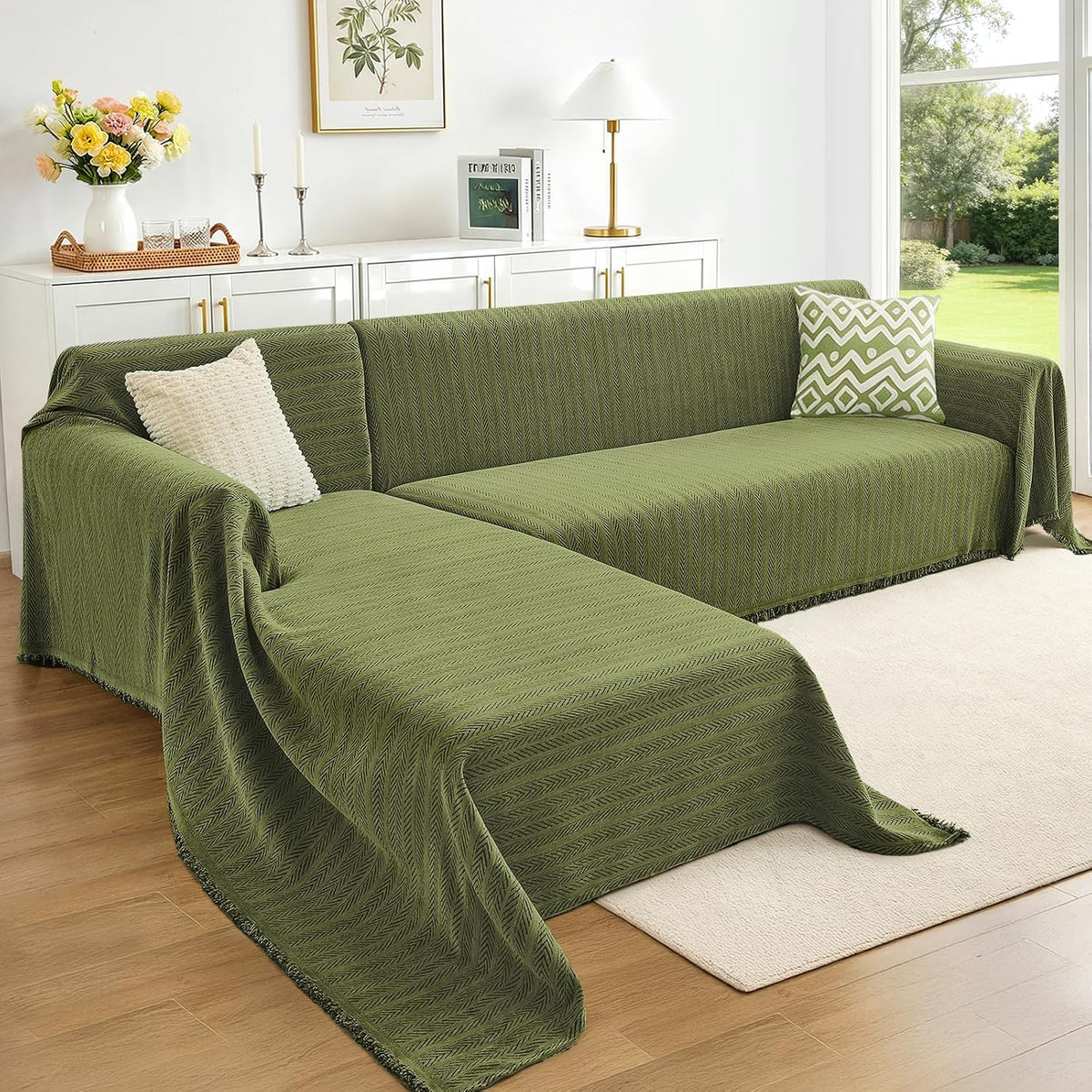 L-shaped sectional covered in olive-green herringbone fabric with a textured cream pillow and green-pattern cushion.