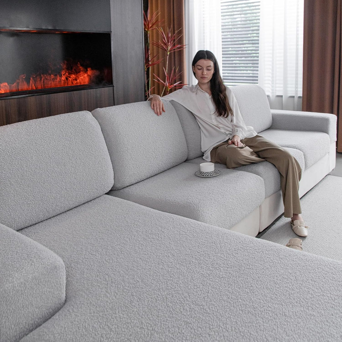 Ivory textured sectional slipcovers on a large sofa with a woman reclining and a cup on the seat.