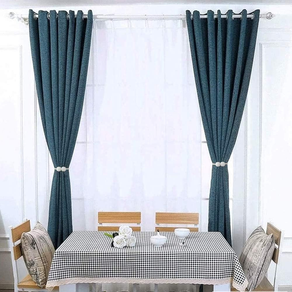 Dining room with teal curtains held at mid-height by white beaded magnetic tiebacks beside a sheer curtain.