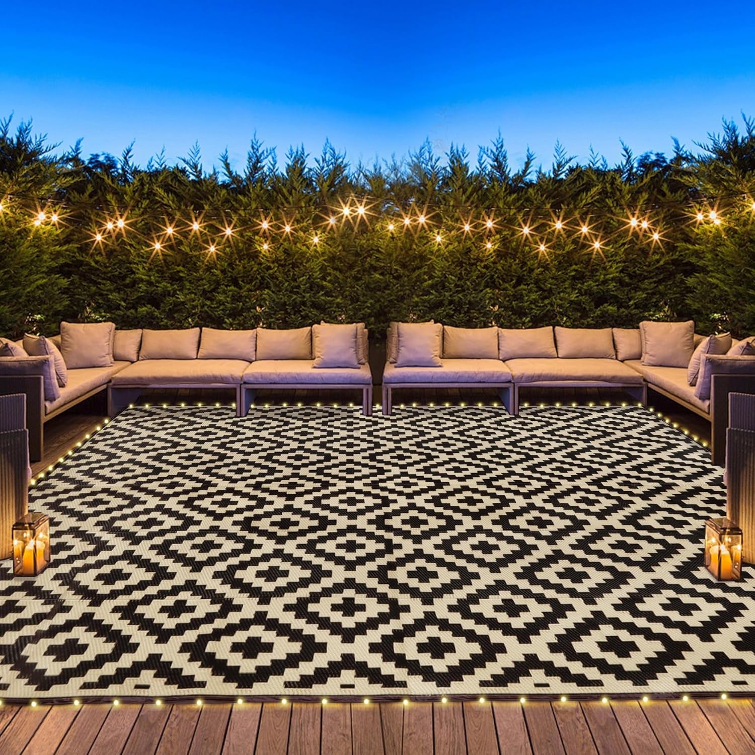 Nighttime backyard lounge with string lights and a black-and-white patterned outdoor rug.
