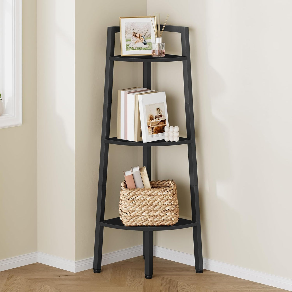 Close-up of the upper three shelves in black corner ladder shelf showing framed photo, books and woven basket