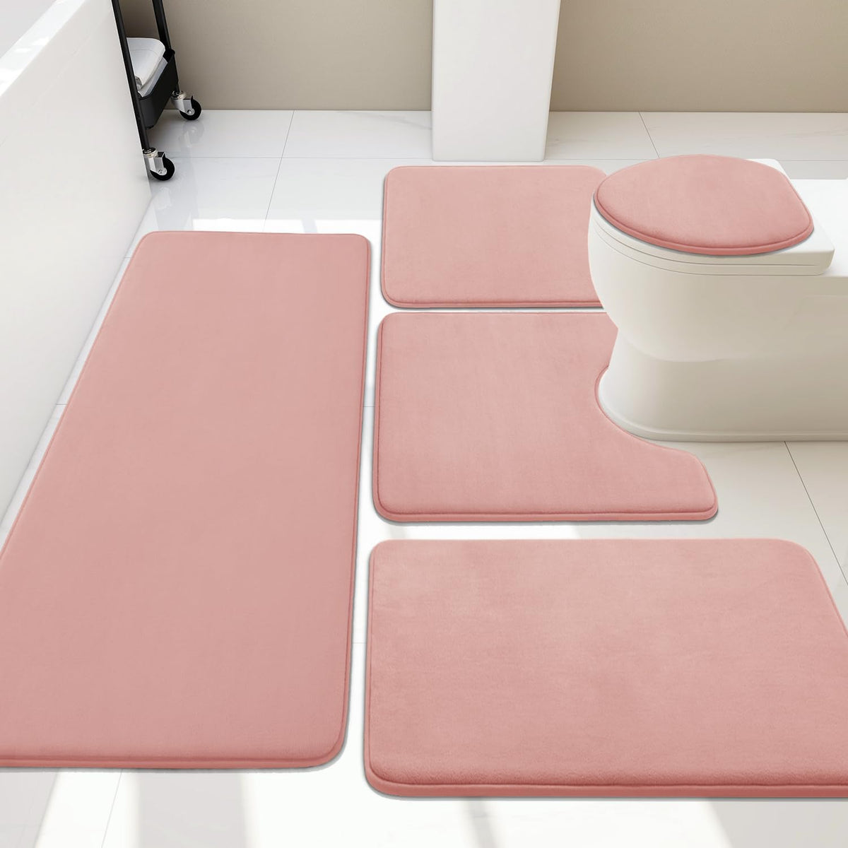 Overhead view of a four-piece pink bath rug set arranged around a toilet and tub.